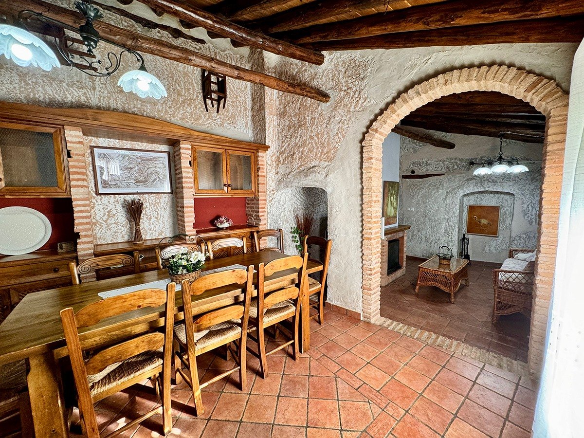 Comedor de estilo rural con arcos de ladrillo y chimenea en Las Grullas Casa Rural